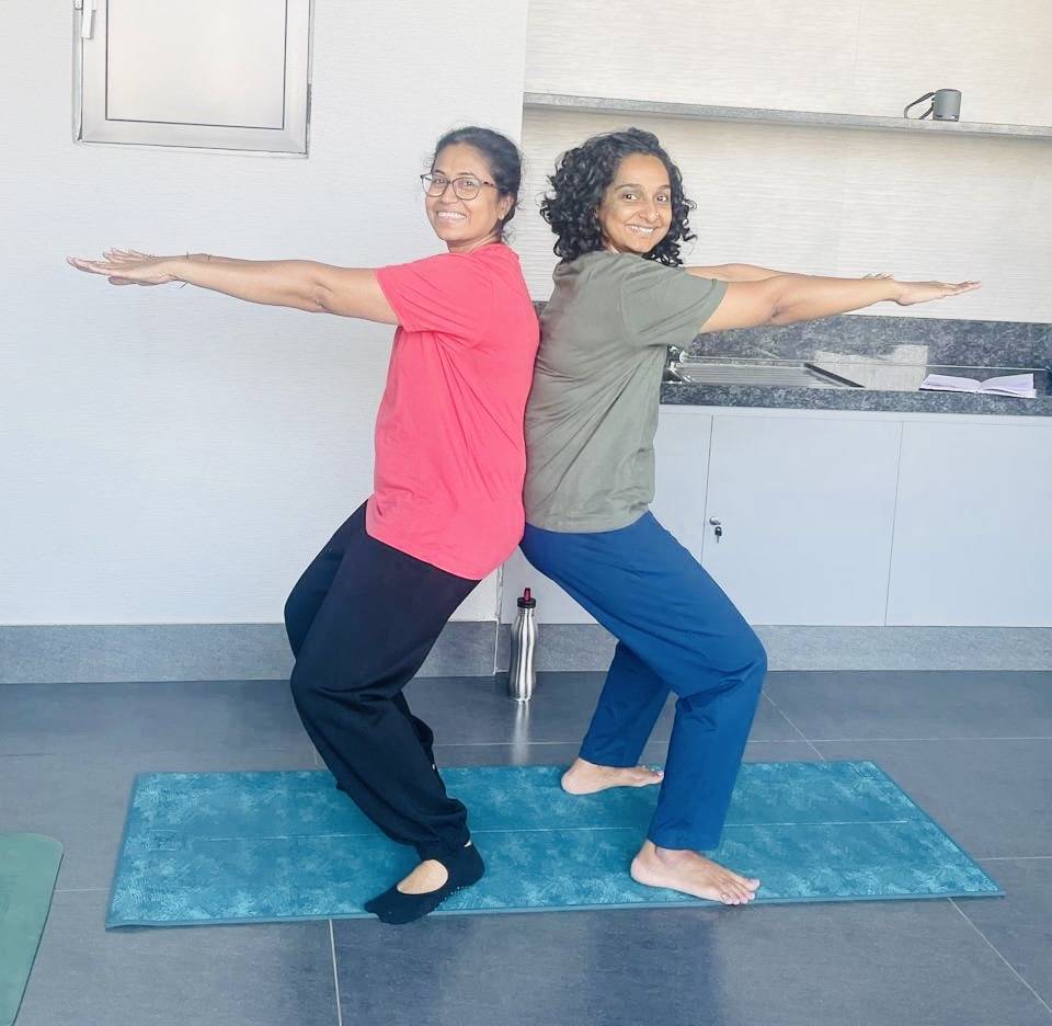 Two students in partner chair pose during a yoga session