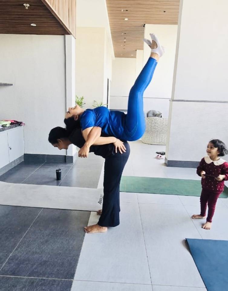 Partner acro yoga with a child watching