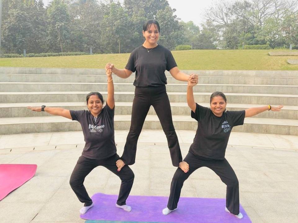 Three students in an outdoor group pyramid pose