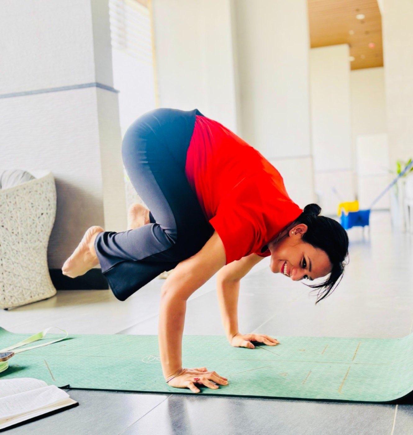 Pallavi demonstrating an arm-balance yoga posture